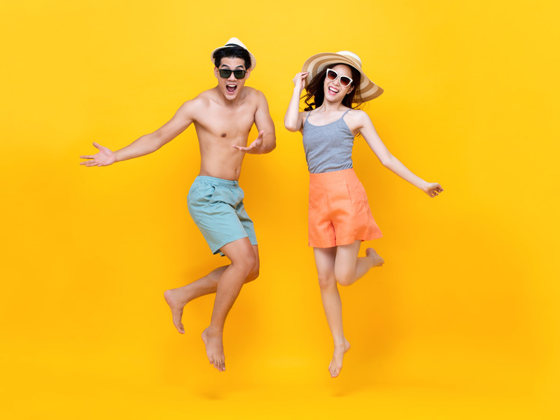 Two people dancing in beach wear to illustrate how to manage veins in summer