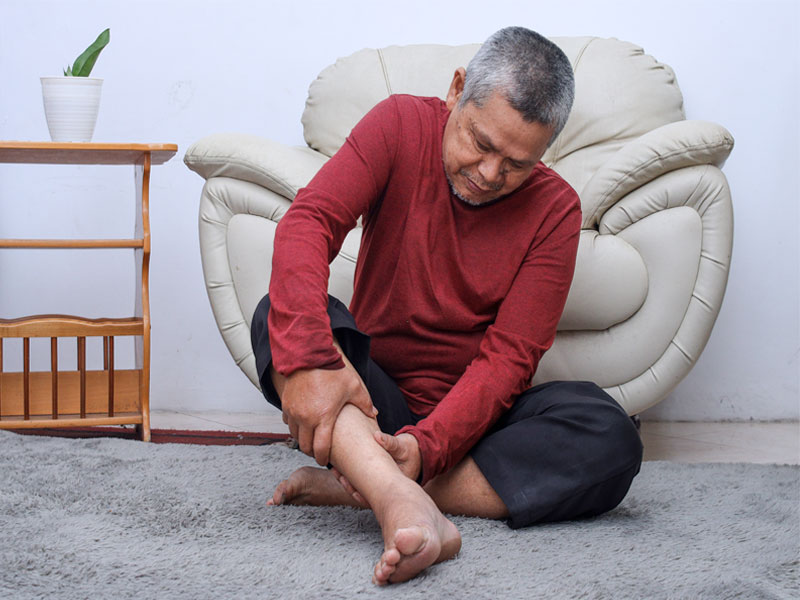 senior man holding calf to illustrate possible links between muscle cramps and varicose veins